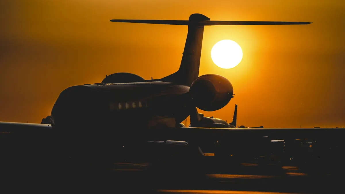 Business jet silhouetted on the runway at sunset