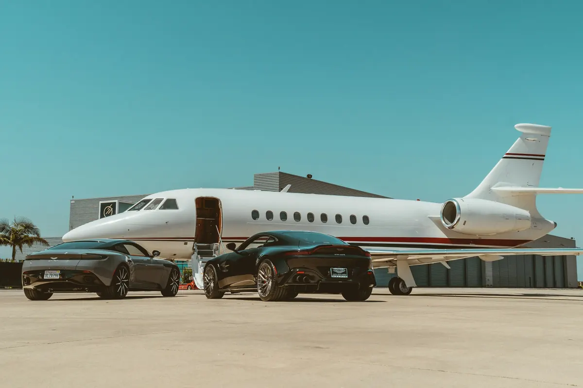Business jet parked on a ramp beside two cars